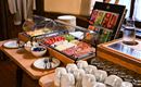 A lovingly arranged breakfast buffet with fresh fruits, sausage and cheese varieties. Dishes and glasses are neatly arranged on a table.