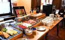 A rich breakfast buffet with fresh fruits, cold cuts, and drinks. The table is beautifully set and offers a cozy atmosphere.