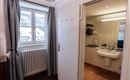 A bright room with a window and a radiator.  
On the right side is the bathroom with modern facilities.