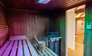 A modern sauna with wooden benches and colorful lights. In the background, there is a bucket and a stove.