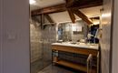 A modern bathroom with wooden details and a large shower. The washing area has an elegant wooden shelf and bright tiles.