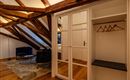 A cozy room in the attic with visible wooden beams. There is a wardrobe, a couch, and a stylish carpet.