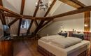 A cozy bedroom with a large double bed and a warm wooden ceiling. The room is bright and modernly furnished, ideal for a relaxing stay.