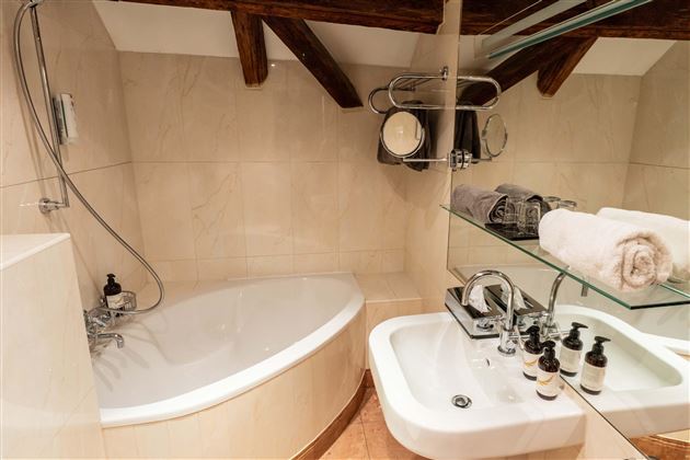 An elegant bathroom with a modern bathtub and a shower. Fresh towels and toiletries are laid out on the sink.