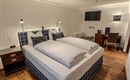 A modern hotel room with a large double bed and wooden floor. There is a desk and a television on the wall.