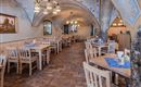A cozy restaurant with wooden tables and chairs. The walls are designed with decorative elements and an arch.