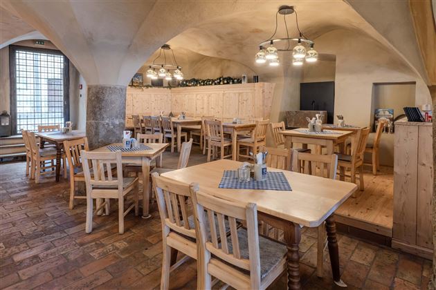 A cozy restaurant with wooden tables and chairs. The warm light sources and the rustic decor create an inviting atmosphere.