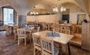 A cozy restaurant with wooden tables and chairs. The warm light sources and the rustic decor create an inviting atmosphere.