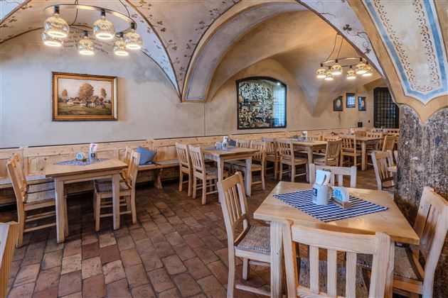 A cozy restaurant with wooden tables and chairs. The walls are decorated in warm colors and decorations.