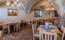A cozy restaurant with wooden tables and chairs. The walls are decorated in warm colors and decorations.