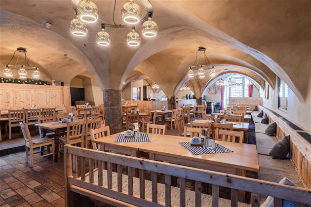 A cozy restaurant with wooden furniture and a warm atmosphere. Large tables and appealing lighting enhance the inviting ambiance.