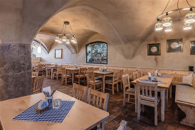 A cozy restaurant with wooden tables and chairs. The walls are neutrally colored and the ceiling has beautiful arches.