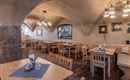 A cozy restaurant with wooden tables and chairs. The walls are neutrally colored and the ceiling has beautiful arches.