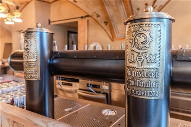 An elegant beer outlet with ornate taps. The wooden counter and rustic style give the location a cozy atmosphere.