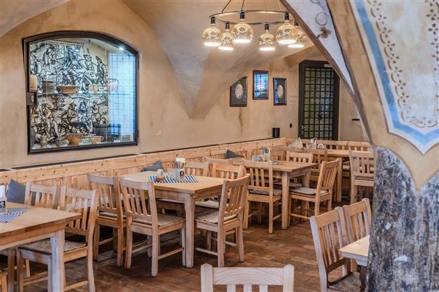 A cozy restaurant with wooden tables and chairs. The walls are decorated and create an inviting atmosphere.
