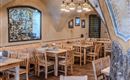 A cozy restaurant with wooden tables and chairs. The walls are decorated and create an inviting atmosphere.