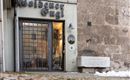 A shop named "Golden Eugl" is visible. The facade is plain and modern, with a wrought-iron gate and a stone wall in the background.
