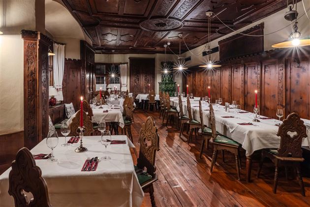 An elegant restaurant with wooden furniture and lovingly set tables. The warm lighting creates an inviting atmosphere.