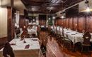 An elegant restaurant with wooden furniture and lovingly set tables. The warm lighting creates an inviting atmosphere.
