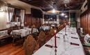 A cozy restaurant with wooden furniture and elegant table decoration. The tables are set for a festive meal and adorned with red candles.