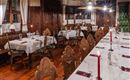 A cozy restaurant with elegant wooden furniture and tablecloths. Red candles create a warm atmosphere.