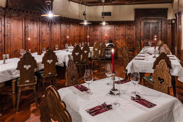 A cozy restaurant with wooden walls and elegant tablecloths. Red candles and fresh dishware give the atmosphere an inviting character.