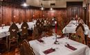 A cozy restaurant with wooden walls and elegant tablecloths. Red candles and fresh dishware give the atmosphere an inviting character.