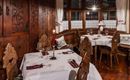 A cozy restaurant with wooden interior and elegant table settings. The atmosphere is warm and inviting, ideal for a romantic dinner.