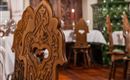 A traditional restaurant with intricately carved wooden chairs. In the background, you can see a cozy atmosphere with laid tables.