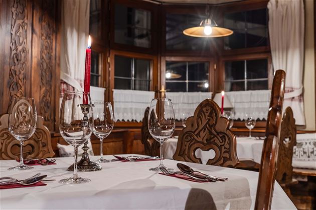 A cozy restaurant with antique wooden interior. Glasses and red candles are on the tables for a romantic atmosphere.