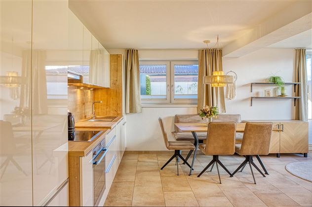 Une cuisine moderne avec un coin repas. Des couleurs claires et beaucoup de lumière naturelle créent une atmosphère accueillante.