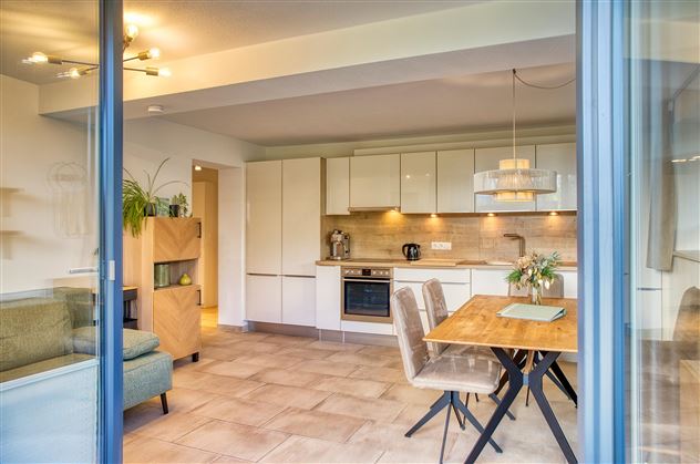 Une cuisine moderne avec des meubles clairs et un coin repas. L'espace est accueillant et bien éclairé.