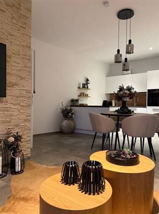 Ein modernes Wohnzimmer mit einer gemütlichen Essgruppe und stilvollen Dekorationselementen. Die warmen Holztöne harmonieren mit der eleganten Einrichtung.