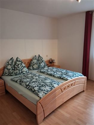 Een gezellige slaapkamer met twee aparte bedden en een vloer die op licht hout lijkt. Het beddengoed heeft een tropisch bladpatroon en een aangename sfeer.