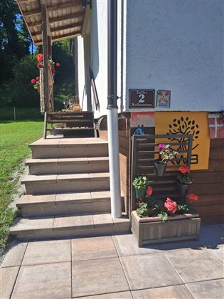 Een mooie huisingang met trappen en een bloeiende bloembak. De sfeer is vriendelijk en uitnodigend.