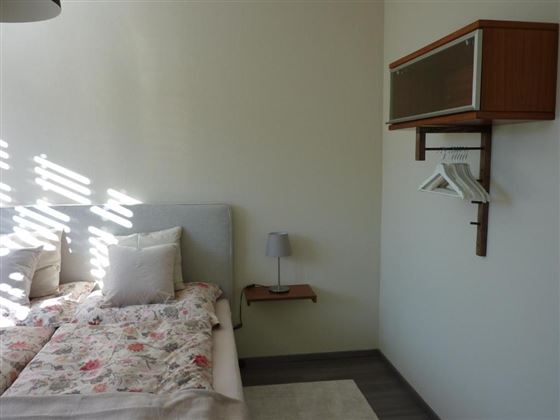 A cozy bedroom with a bed in gentle colors and a minimalist decor. Soft light falls through the window and illuminates the room.