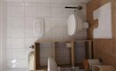Ein schlichtes Badezimmer mit weißen Fliesen und einem modernen Toilette. Die Ausstattung umfasst eine Handtuchablage und einen kleinen Abfallbehälter.