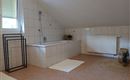 Ein geräumiges Badezimmer mit einer Badewanne und hellen Fliesen. Es gibt einen Heizkörper und eine Fenster mit natürlichem Licht.