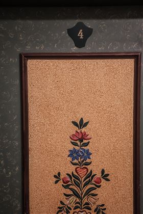 Eine dekorierte Tür mit einer Blumenmotivanordnung und der Nummer vier oben. Die Farbgestaltung ist warm und einladend.