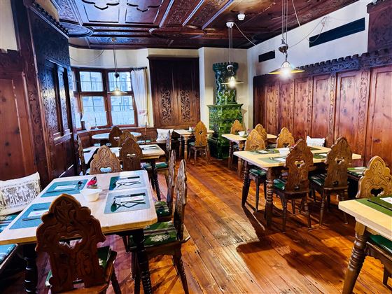 A cozy dining room with rustic wooden furniture and beautiful chairs. The room is designed with traditional wooden paneling and warm lighting.