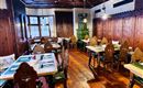 A cozy dining room with rustic wooden furniture and beautiful chairs. The room is designed with traditional wooden paneling and warm lighting.