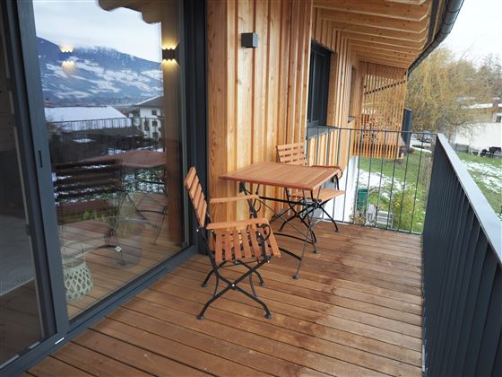 Un balcone accogliente con un tavolino e due sedie. L'ambiente mostra un bel paesaggio con montagne sullo sfondo.