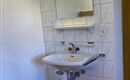 A modern bathroom with a sink and a large mirror. The walls are tiled and the floor is made of wood.