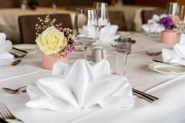 Un service de table élégant avec des serviettes pliées, des verres et des plantes fleuries. La décoration de table dégage une atmosphère festive.