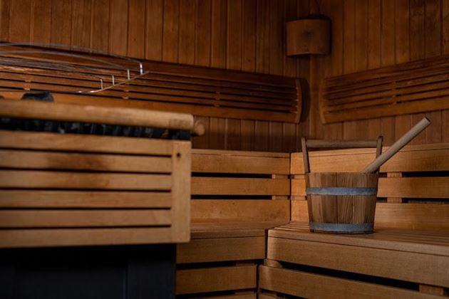 A cozy sauna area with wooden benches and a bucket. The atmosphere is warm and inviting.