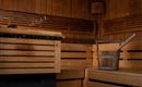 A cozy sauna area with wooden benches and a bucket. The atmosphere is warm and inviting.