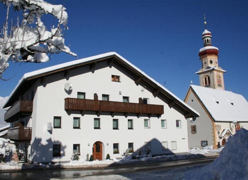 A charming building in the snow with a traditional church tower next to it. The sky is clear and blue, which beautifully illuminates the winter scene.