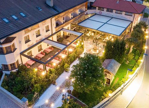 A modern hotel with an inviting outdoor area and seating outside. The surroundings are lush and well-lit, creating a cozy atmosphere.