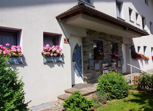An inviting house with a beautiful entrance. Colorful flowers adorn the windows and the garden.