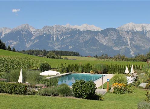 A beautiful pool in a rural setting with a view of majestic mountains in the background. The landscape is green and inviting, perfect for relaxation.